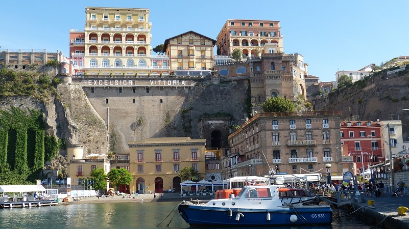 Marina Grande, Sorrento Färgglada byggnader och hotell vid Sorrentos gamla hamn, med båtar förtöjda i det lugna vattnet nedanför klipporna.